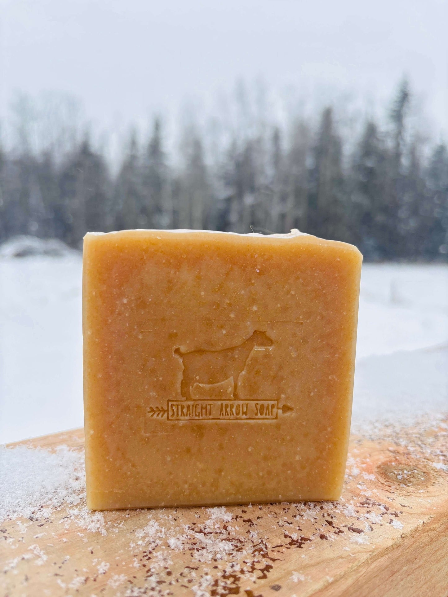 Palo Santo + Cedarwood goat milk soap bar on snowy wooden background, ideal for bubble bath & lotions.