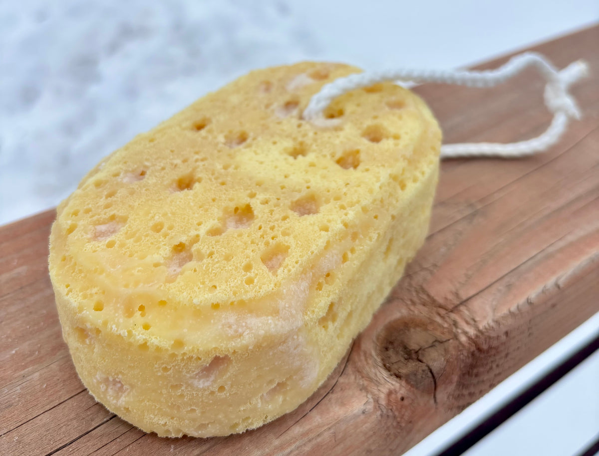 Yellow loofah soap filled sponge on a wooden surface with a blurred background