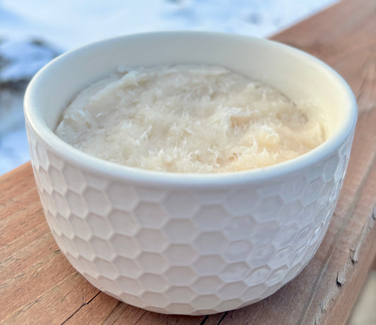 White textured bowl filled with shaving soap on a wooden surface