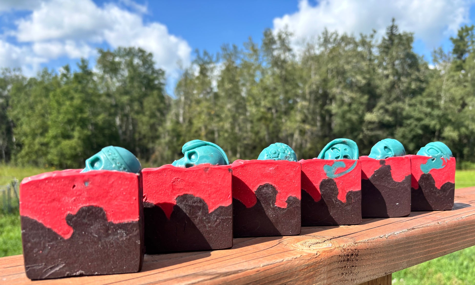 Straight arrow farms goat milk soap, scented in lost Cherry fragrance in a Halloween themed bar, layered in red and black with a green skull embed on top. 