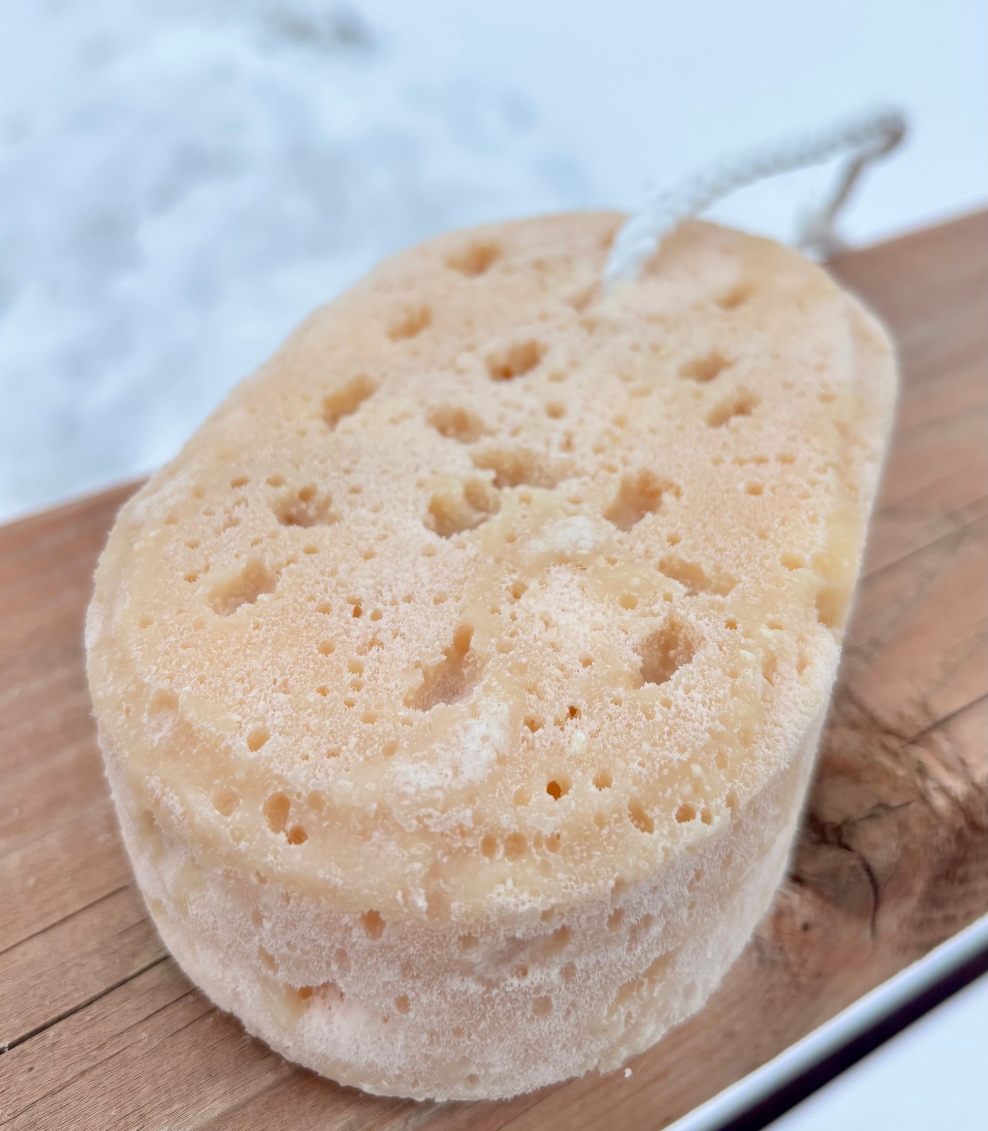 Natural soap filled sponge on a wooden surface with a blurred background