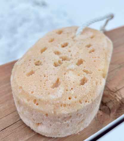 Natural soap filled sponge on a wooden surface with a blurred background