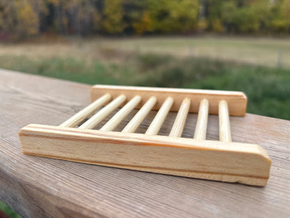 Wooden soap dish on a wooden surface with a blurred natural background
