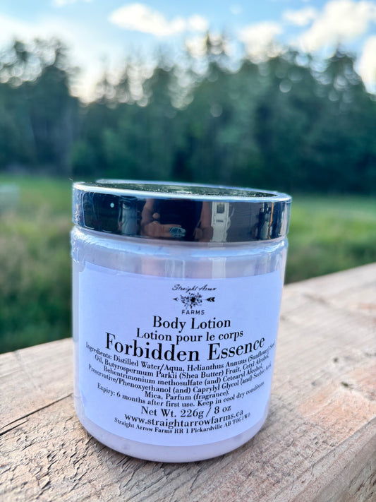 Body lotion jar labeled 'Forbidden Essence' on a wooden surface with a natural background
