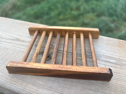 Wooden soap dish on a wooden surface with a blurred green background