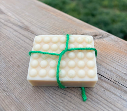 Bar of soap with a green string on a wooden surface