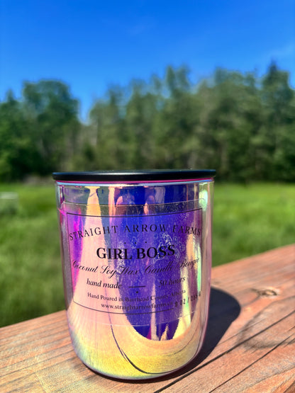 Candle labeled 'Girl Boss' by Straight Arrow Farms on a wooden surface with a natural background