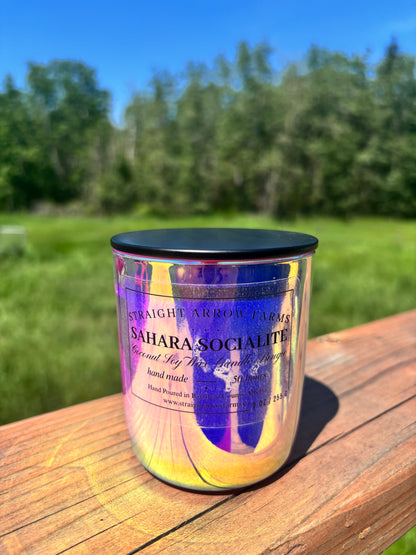 Candle jar labeled 'Sahara Socialite' on a wooden surface with a natural background