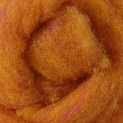 A basket containing multicolored wool dryer balls displayed outdoors with a scenic background.