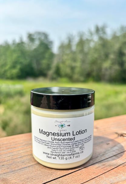 Straight Arrow Farms Magnesium Lotion Unscented, 135g jar with black lid, photographed outdoors on a wooden surface with a green field background