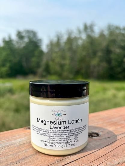 Straight Arrow Farms Magnesium Lotion Lavender, 135g jar with black lid, photographed outdoors on a wooden surface with a green field background